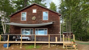 Eine rustikale Holzhütte mit einer Terrasse, Sitzgelegenheiten im Freien und einem Grill.