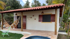 Una casa con piscina, una hamaca y una silla.