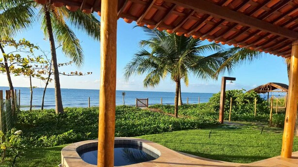 Un área de piscina con un jacuzzi, rodeada de palmeras y vista al océano.