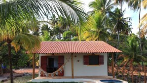 Una pequeña casa con techo de tejas, una hamaca y una piscina.