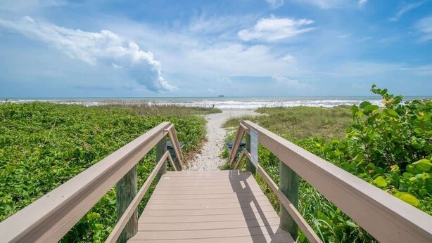 A wooden boardwalk leading to a beach with a clear sky. - Oceanfront Complex | Heated Pool/Tennis | Grnd FL (Cocoa Beach)