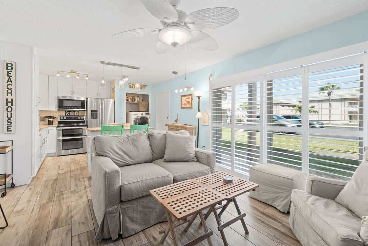 A modern kitchen with white cabinets, stainless steel appliances, and a ceiling fan.