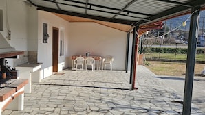 An outdoor patio with a barbecue grill, a table with chairs, and a view of a garden. - Paikos Townhouse is a Unique 220 sq.m. Residence with Garden, Pavilion & Orchard (Κωνσταντία)