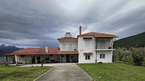 A two-story house with a red-tiled roof, a balcony on the second floor, and a driveway leading to the entrance. - Paikos Townhouse is a Unique 220 sq.m. Residence with Garden, Pavilion & Orchard (Κωνσταντία)