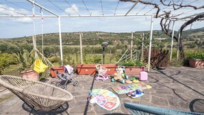 An outdoor patio with a view of hills, a pergola, a baby stroller, a play mat, and a wicker chair. - La Villa del Relax - Two Bedroom Villa, Sleeps 4 (Sennori)