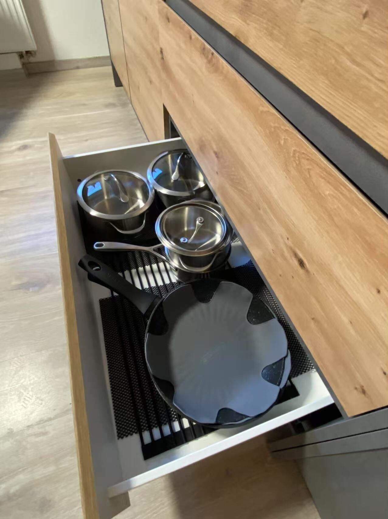 A kitchen drawer with pots, pans, and a spatula.