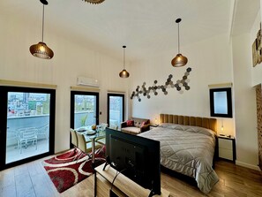 Ein modernes Schlafzimmer mit einem großen Bett, einem Fernseher und einer Essecke mit Blick auf die Stadt.