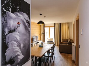 A dining area with a wooden table and chairs, a sofa, and a large window with curtains. - Chalet in Combloux With Mont-blanc Views (Combloux)