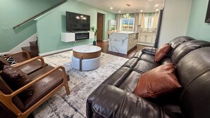 A living room with a leather sofa, a coffee table, and a TV mounted on the wall.