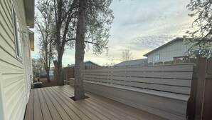 A wooden deck with a wooden fence and a tree.