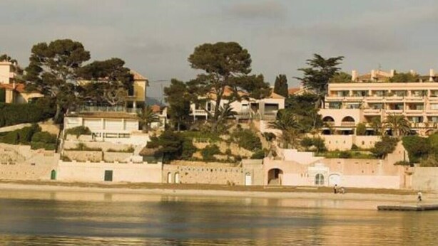 A coastal hotel with multiple buildings, a waterfront, and trees. - 180° sea view, direct beach access, close to town center (Bandol)