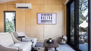 En moderne stue med en beige sofa, et lille bord med en plante og et indramet skilt på væggen.