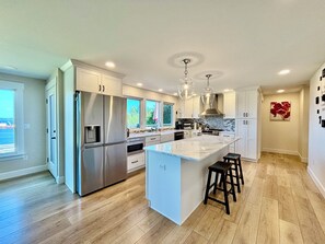 A modern kitchen with stainless steel appliances, a large island, and a view of the ocean.