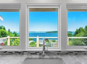 A kitchen with a large window overlooking a scenic view of a body of water and greenery. - Enjoy the view! (Port Orchard)