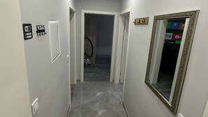 Un pasillo con suelo pulido, una puerta con lector de tarjeta de acceso, un cartel de Wi-Fi y un espejo en la pared.