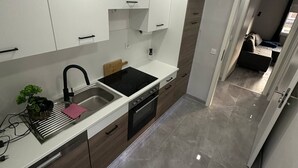 Una cocina moderna con armarios blancos, un lavamanos negro y un horno empotrado.