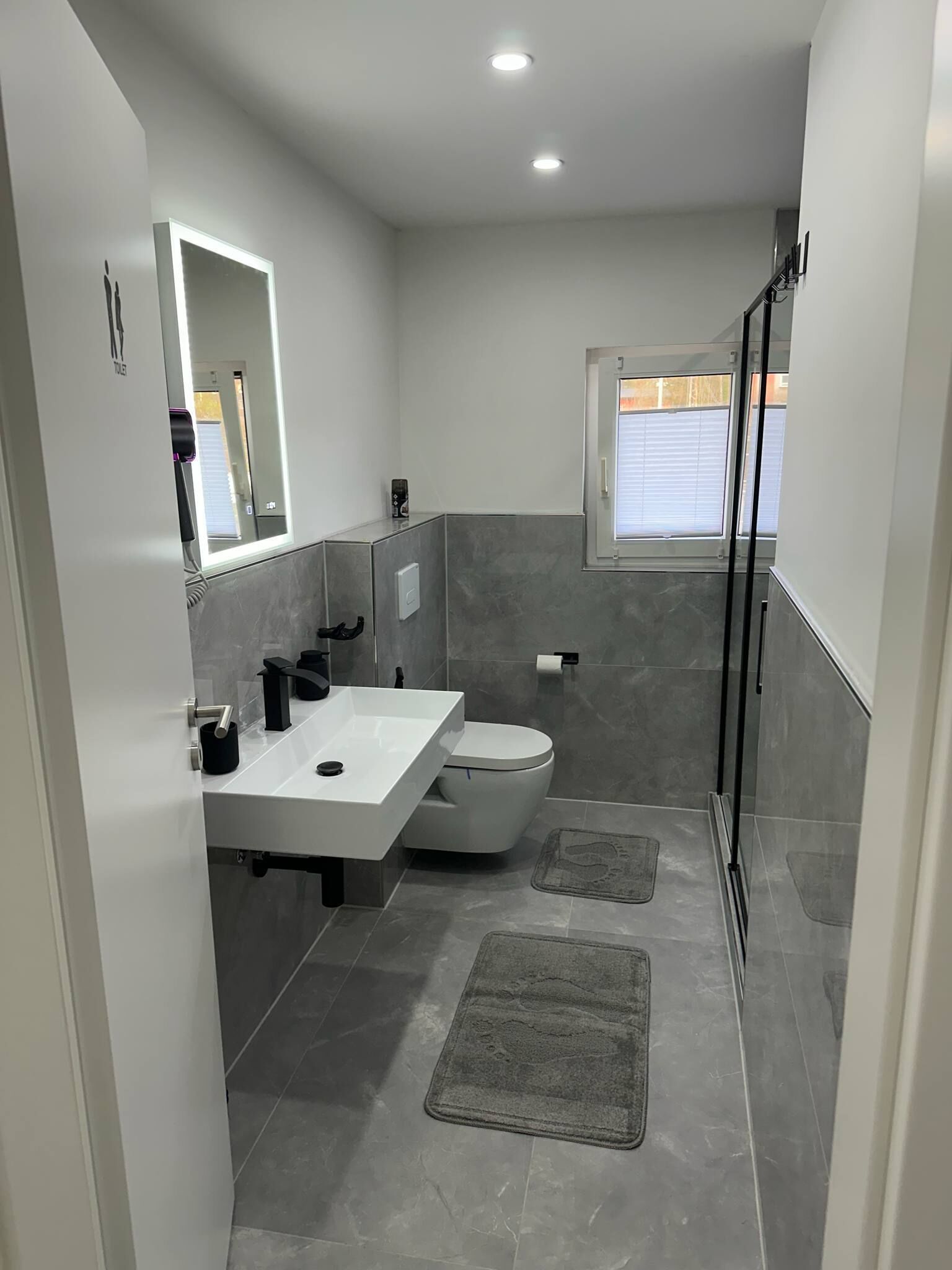 Een moderne badkamer met een wit wastafel, toilet en een douchecabine van glas.