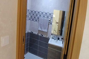 Bathroom features a large mirror above the sink, toilet, and shower area.