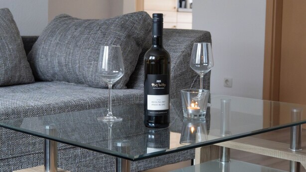 Una sala moderna con una mesa de centro de vidrio, un sofá y dos copas de vino.