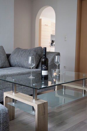 A modern living room with a glass coffee table, a sofa, and two wine glasses. - Vacation in one of the most beautiful regions of Saxony - the Ore Mountains (Wolkenstein)