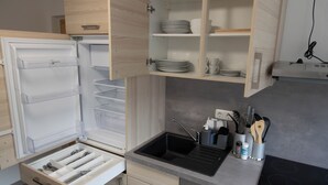 Una cocina compacta con nevera integrada, un lavabo y armarios de madera.