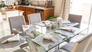 A dining table set with placemats, cutlery, and a pitcher. - Wake up to the best panoramic views in this cozy 3-bedroom house. (West Jordan)