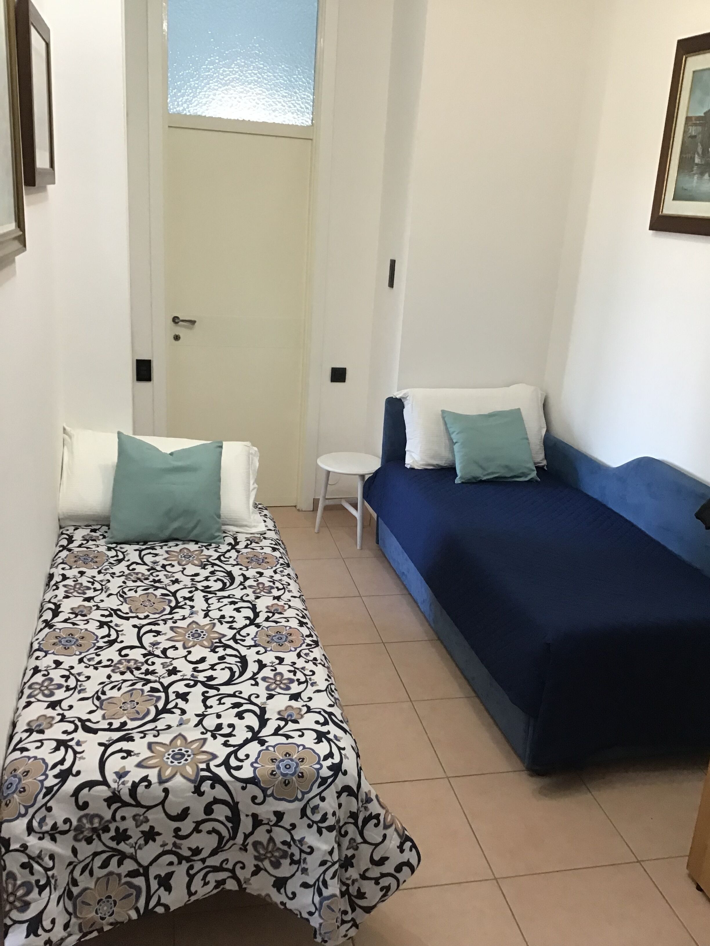 Une petite pièce, de taille modeste, avec un lit à gauche, un canapé à droite et une petite table au centre.