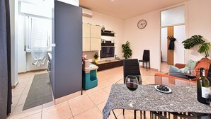 A modern living room with a dining area, a kitchen in the background, and a large window. - Whole cozy apartment ;Bright, ideal, for families;Single couples. (Lazzate)