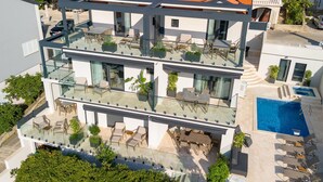 Een meerlaags hotel met balkons, buiten zitplaatsen en een zwembad.