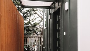 A narrow outdoor corridor with a wooden fence, a metal gate, and a concrete path leading to a building entrance. - Rooftop Lake Union & Skyline Views -- New Eco Home in Wallingford (Seattle)