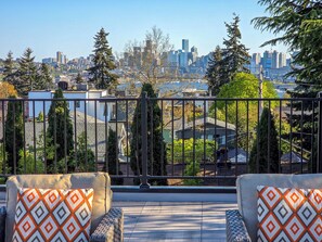 A balcony with two chairs and a view of a city skyline.