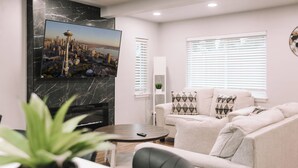 A living room with a flat-screen TV, a sofa, a coffee table, and a potted plant. - Rooftop Lake Union & Skyline Views -- New Eco Home in Wallingford (Seattle)