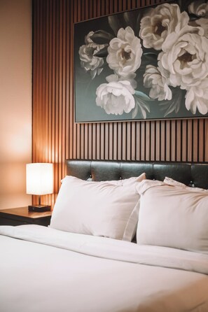 A hotel room with a bed, a nightstand, a lamp, and a floral painting on the wall. - Rooftop Lake Union & Skyline Views -- New Eco Home in Wallingford (Seattle)