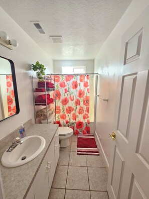 Un baño con inodoro, lavamanos y cortina de ducha.