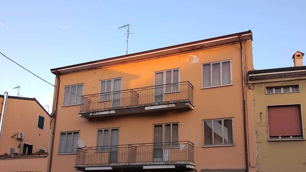 Un immeuble de deux étages, avec un commerce au rez-de-chaussée et un balcon au deuxième étage.