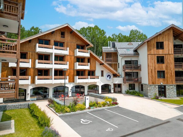 A modern building with multiple balconies, a central courtyard with seating, and a disabled parking space. - Apartment in Serre-chevalier Near Ski Slopes (Saint-Chaffrey)