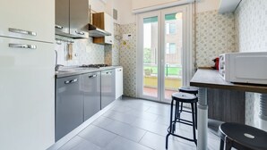 Eine moderne Küche mit grauen Schränken, einem eingebauten Herd und einem großen Fenster.