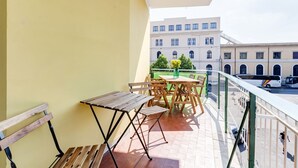 Ein Balkon mit einem Holztisch, Stühlen und einer grünen Flasche.