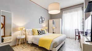 Ein Schlafzimmer mit Bett, Nachttischlampen, einem Kleiderschrank, einem Schreibtisch mit Stuhl und einem Fernseher.
