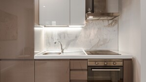 A modern kitchen with a stainless steel sink, a built-in oven, and a range hood. - Jacuzzi Suite – Nikis Collection Trastevere (Roma)