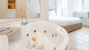 A modern bathroom with a large bathtub, a mirror, and a shower area. - Jacuzzi Suite – Nikis Collection Trastevere (Roma)