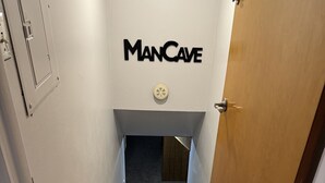 Una escalera con escalones de madera que conduce a una puerta con la inscripción 'ManCave'.