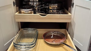 Una cocina con un cajón empotrado que contiene utensilios de cocina y cristalería.