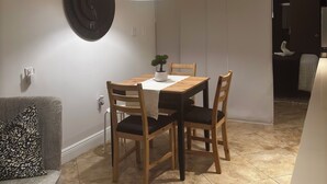 Zona pranzo con tavolo, sedie, lampadario, pianta in vaso e piatto decorativo appeso al muro.