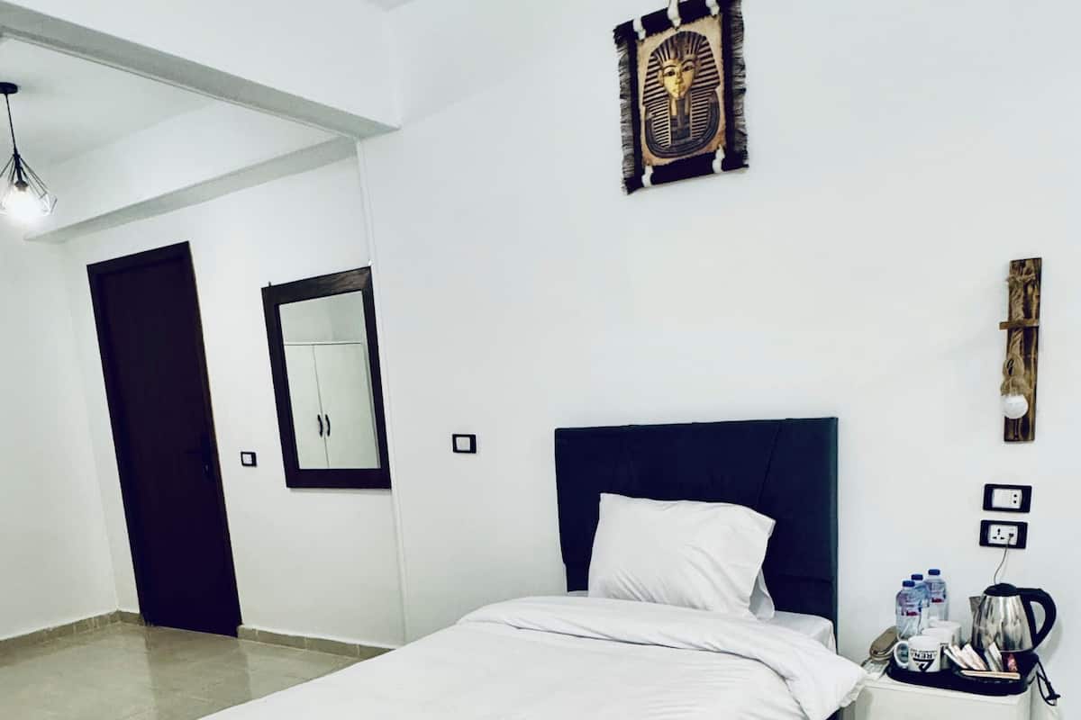 A bedroom with a bed, a nightstand, a mirror, and a wall decoration.