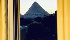 A window view of a pyramid-shaped mountain. - Arena Pyramids View (Giza)