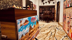 A reception area with a wooden desk, a large poster of the Atena Pyramids, and a world map on the wall. - Arena Pyramids View (Giza)