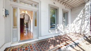 A building entrance with a tiled walkway, white walls, and a door with a glass panel. - Saint Francis in Fitzroy (Fitzroy)