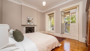 A bedroom with a bed, a fireplace, and a view through a door. - Saint Francis in Fitzroy (Fitzroy)