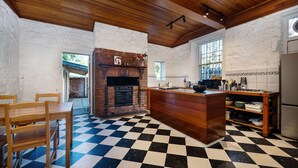 A kitchen with a checkered floor, wooden cabinets, a brick fireplace, and a window with a view. - Saint Francis in Fitzroy (Fitzroy)